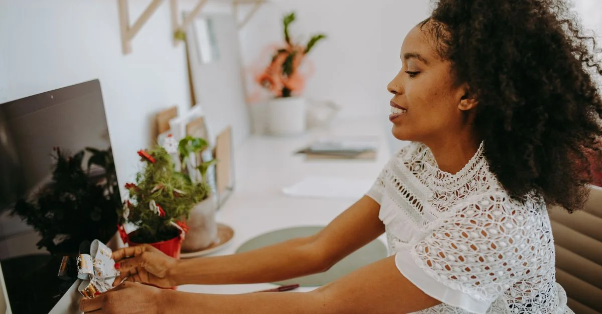 Vue de côté d'une femme organisant un espace de travail à domicile vibrant avec des plantes.