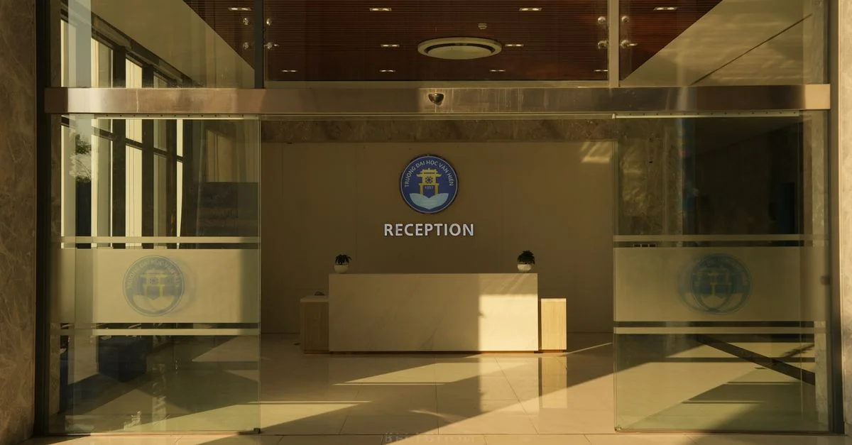 Espace de réception de bureau spacieux avec logo sur le mur et lumière naturelle.
