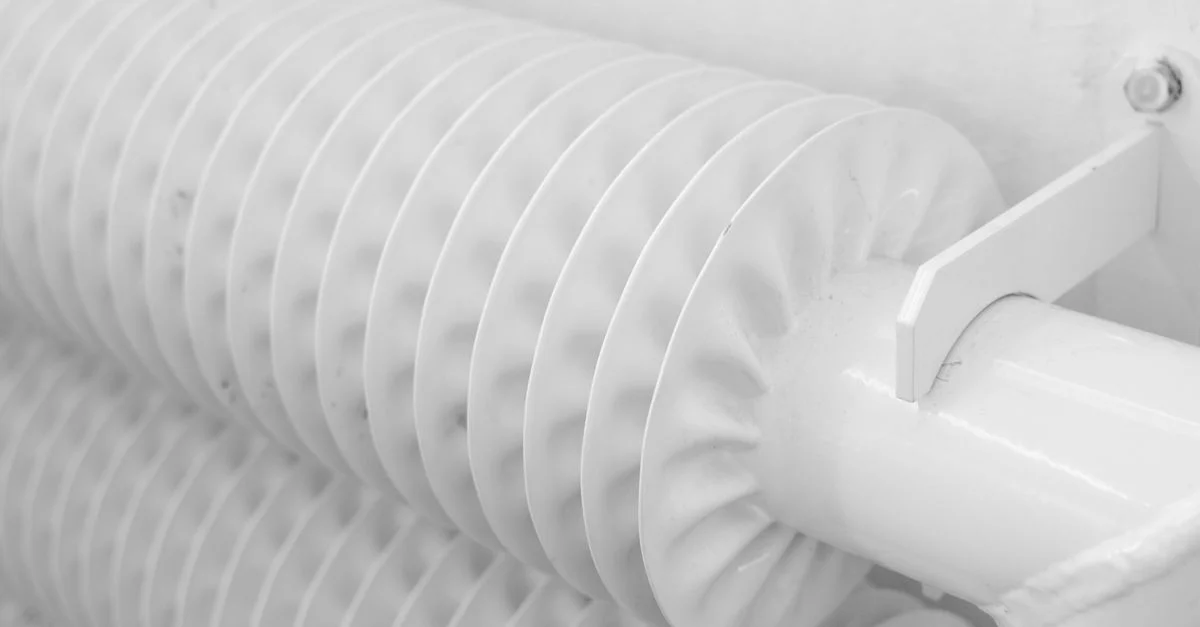 Vue détaillée d'un tuyau de radiateur blanc avec un design à ailettes, mettant en avant des éléments industriels modernes.