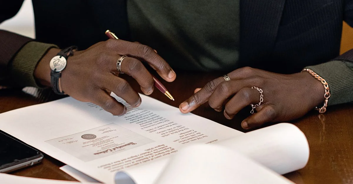 Les mains d'un professionnel signant un document à un bureau, en mettant l'accent sur les détails.