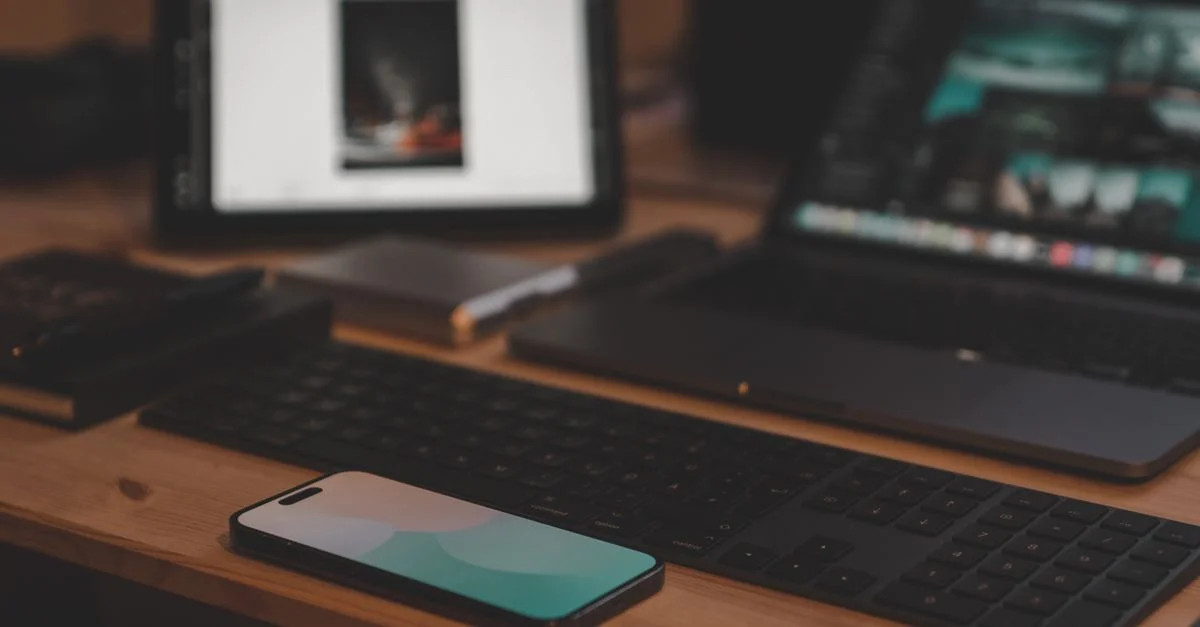 Un bureau contemporain avec un ordinateur portable, un smartphone et une tablette sur un bureau en bois.