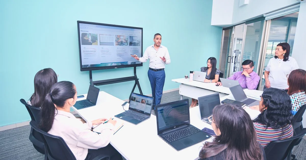 Équipe engagée dans une présentation dans un bureau moderne utilisant la technologie numérique.