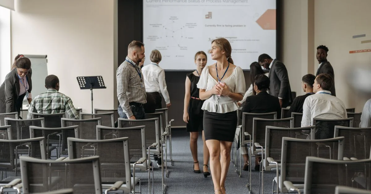 Des professionnels lors d'une conférence d'affaires interagissent avant une présentation dans un bureau moderne.