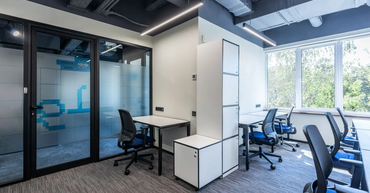 Espace de bureau contemporain lumineux avec des chaises bleues et de grandes fenêtres, offrant un environnement de travail productif.