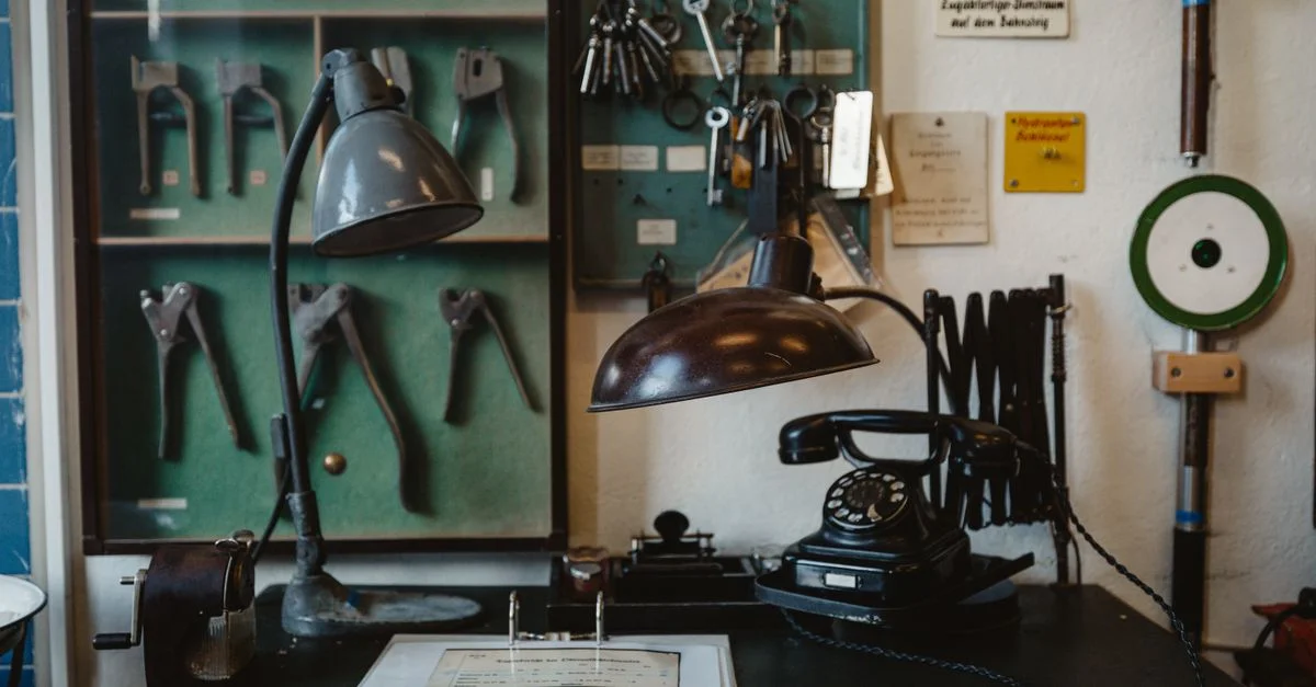 Un bureau d'atelier vintage nostalgique avec des outils classiques, une vieille lampe et un téléphone à cadran, évoquant une époque révolue.