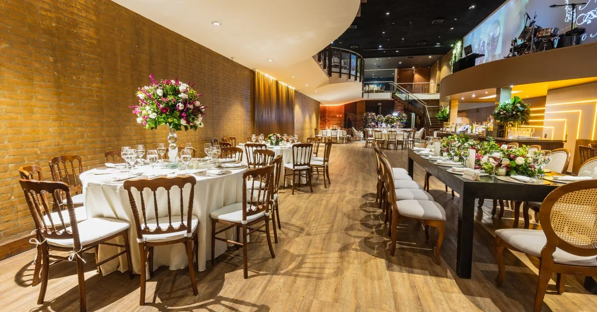 Salle de mariage luxueuse prête pour une réception avec des arrangements de table élégants et une décoration florale.