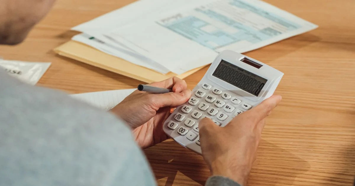 Personne utilisant une calculatrice à un bureau avec des documents financiers. Concept moderne d'affaires.