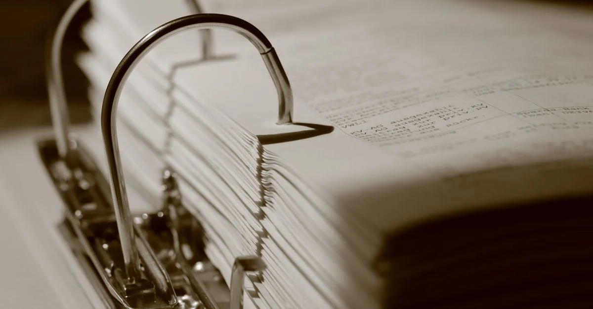 Gros plan détaillé en sépia d'un classeur rempli de documents, mettant en valeur la texture.
