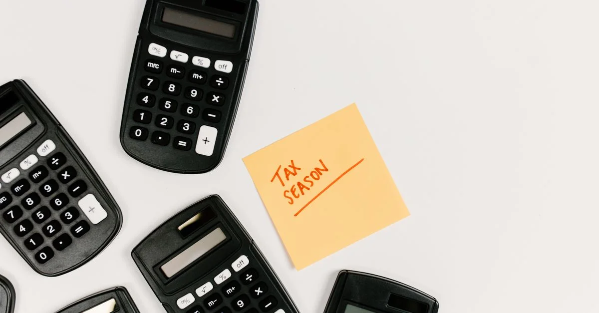Vue de dessus de calculatrices avec une note autocollante pour la saison fiscale sur fond blanc.