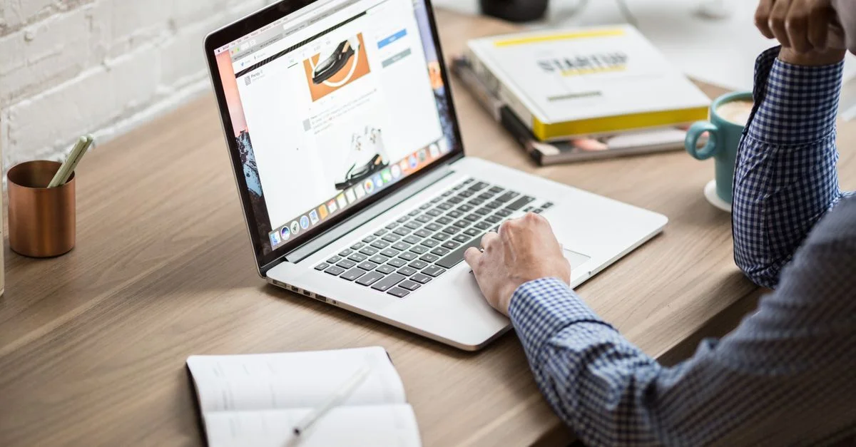 Un adulte travaillant sur un ordinateur portable dans un bureau moderne, illustrant la productivité et la concentration.