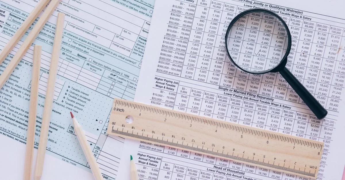 Une vue en plongée montrant des formulaires fiscaux IRS avec des crayons, une règle et une loupe pour la planification financière.
