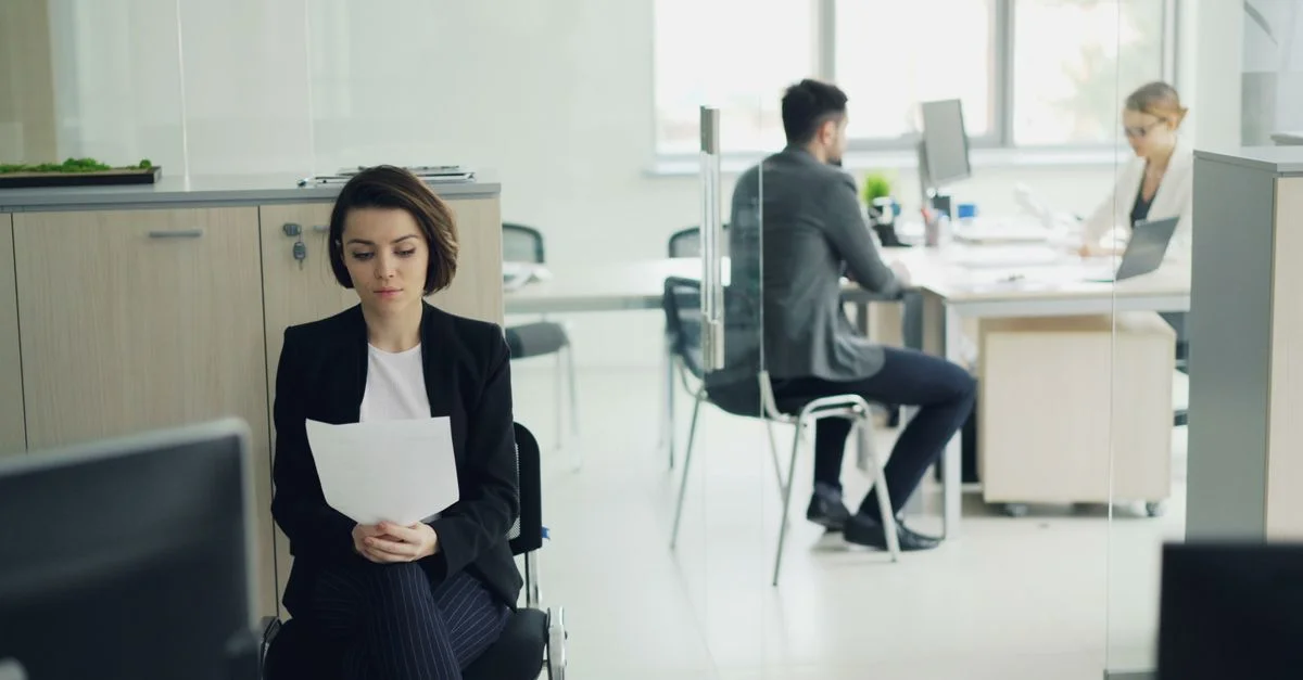 Des professionnels travaillant dans un bureau moderne avec un accent sur une femme assise.