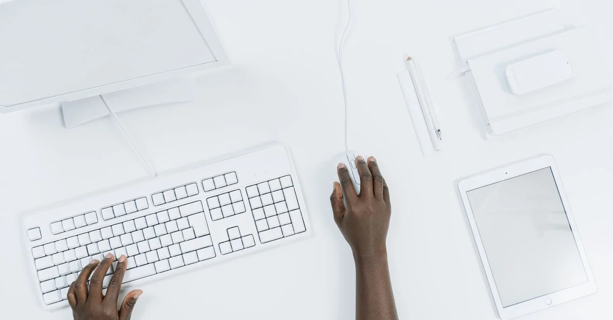 Vue de dessus d'un espace de travail minimaliste avec un ordinateur, un clavier et une tablette.