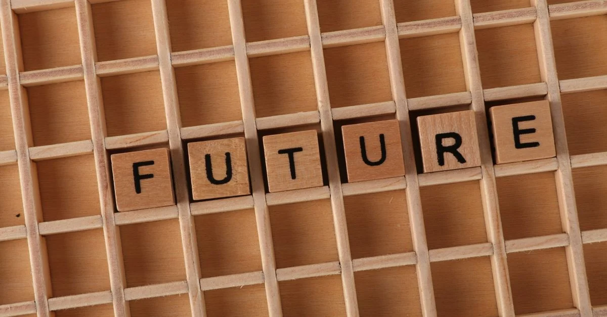 Des lettres en bois forment le mot « FUTUR » sur un fond de grille en bois.