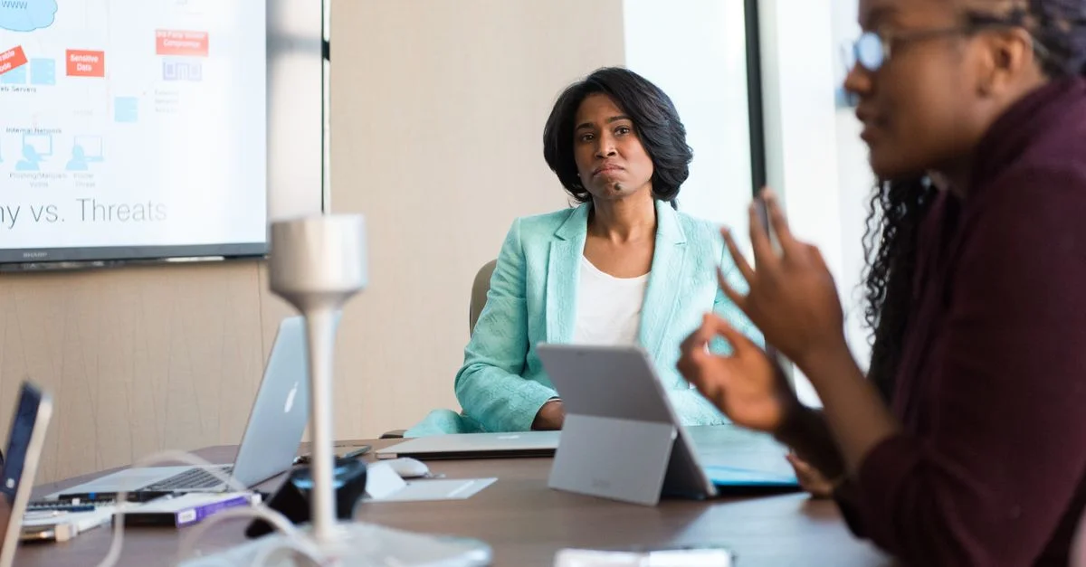 Femmes professionnelles engagées dans une réunion d'affaires, discutant de stratégie avec la technologie sur le lieu de travail.