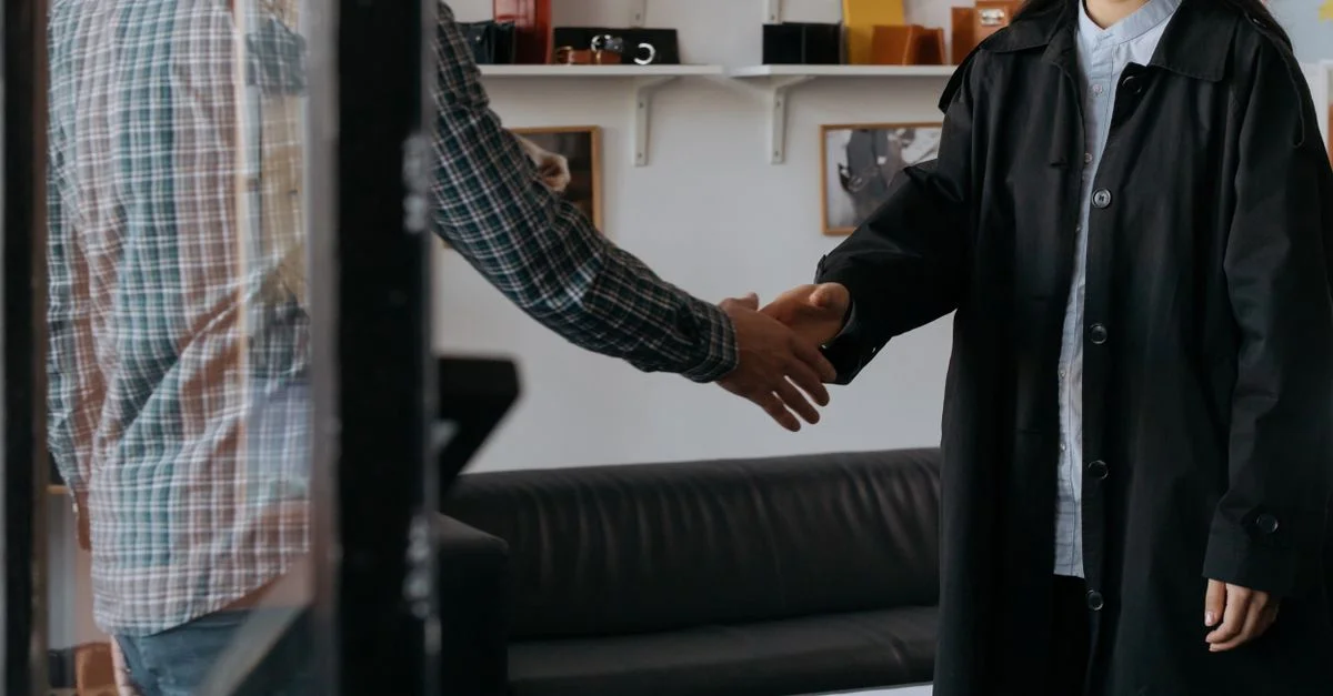 Deux professionnels s'engagent dans une poignée de main, symbolisant un accord réussi dans un bureau contemporain.