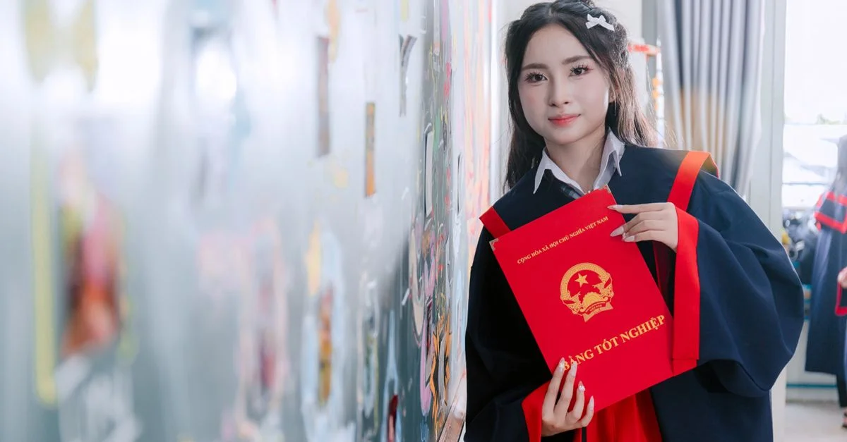 Jeune diplômée en toge universitaire, tenant son diplôme, célébrant sa réussite à l'intérieur.
