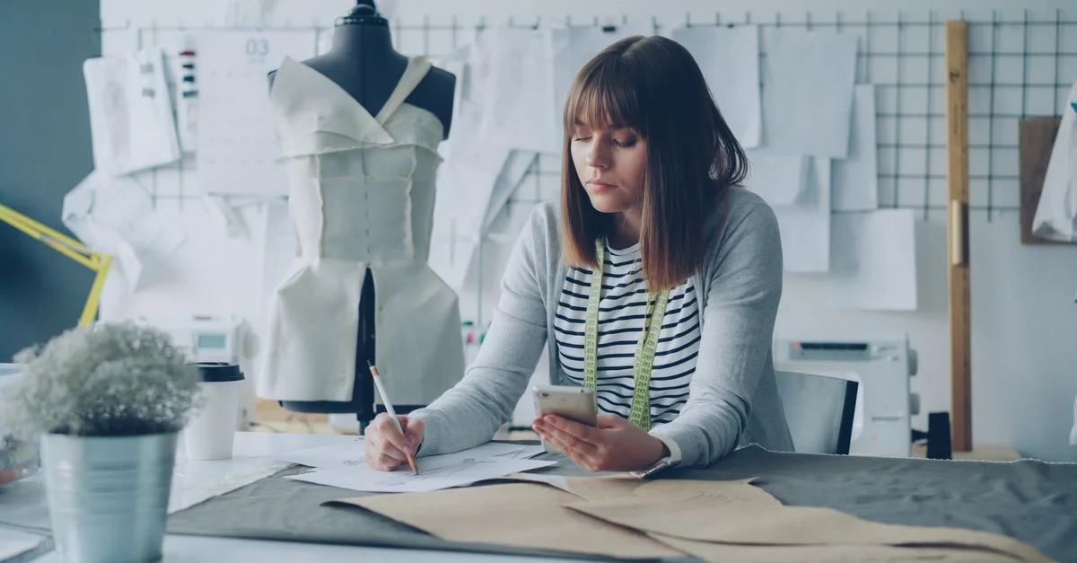 Créateur de mode travaillant sur des patrons de robe avec un mannequin dans un studio élégant.