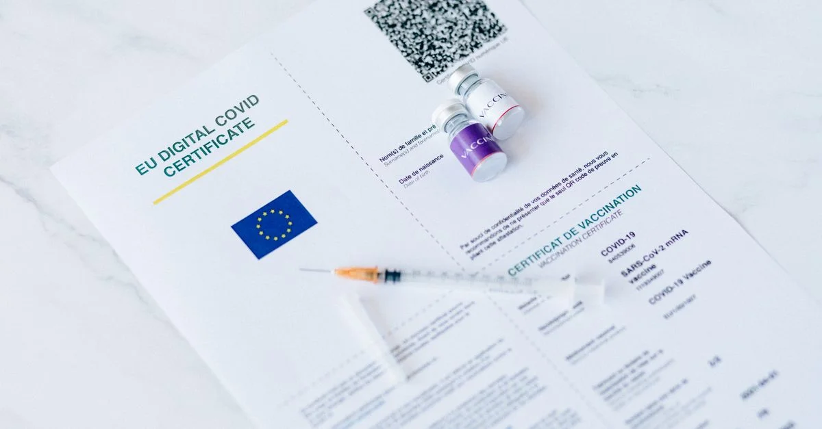 Certificat numérique COVID de l'UE avec des flacons de vaccin et une seringue sur un fond blanc.
