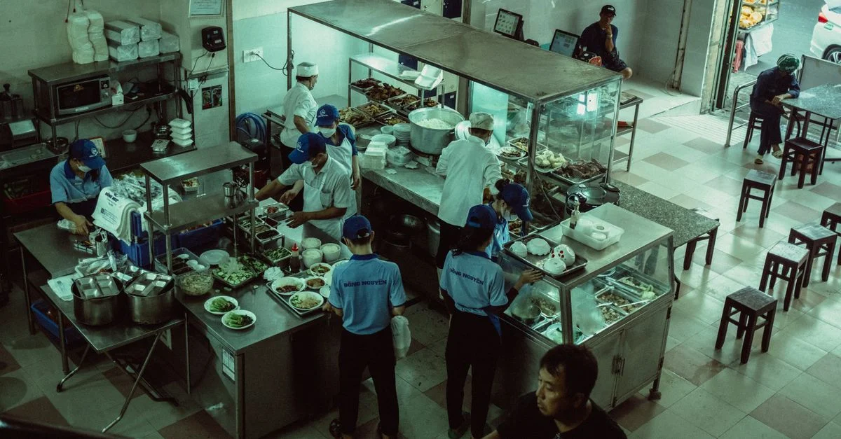 Des chefs préparant des repas dans la cuisine d'un restaurant local, vus d'en haut.