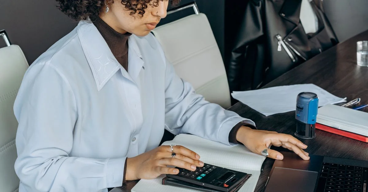 Jeune femme dans un bureau utilisant une calculatrice pour des calculs financiers.