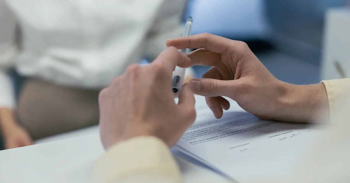 Gros plan sur des mains tenant un stylo lors d'une réunion d'affaires ou de la signature d'un contrat.