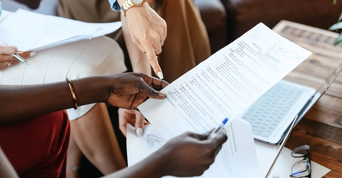Groupe de professionnels passant en revue des documents lors d'une réunion de bureau, mettant l'accent sur le travail d'équipe et la stratégie.
