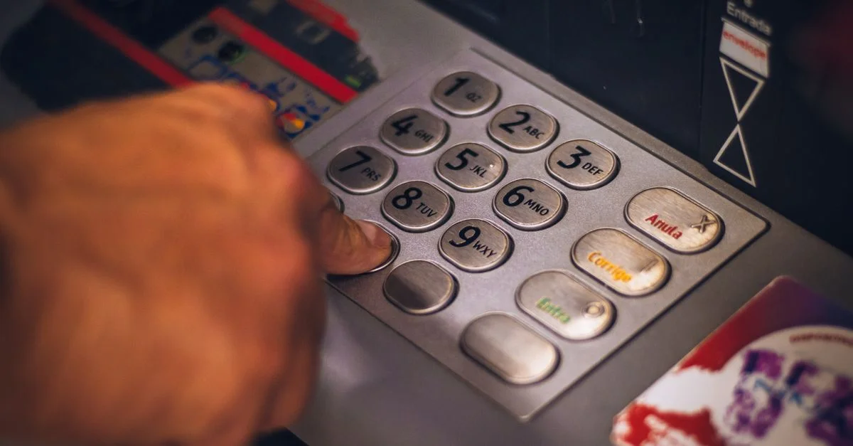 Une main appuyant sur un bouton du clavier d'un distributeur automatique au Brésil, mettant en avant la banque digitale.