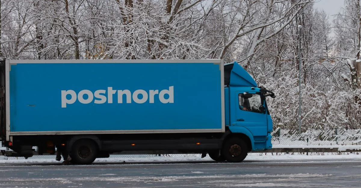 Un camion PostNord bleu garé dans un paysage hivernal enneigé, mettant en avant le transport dans des environnements froids.