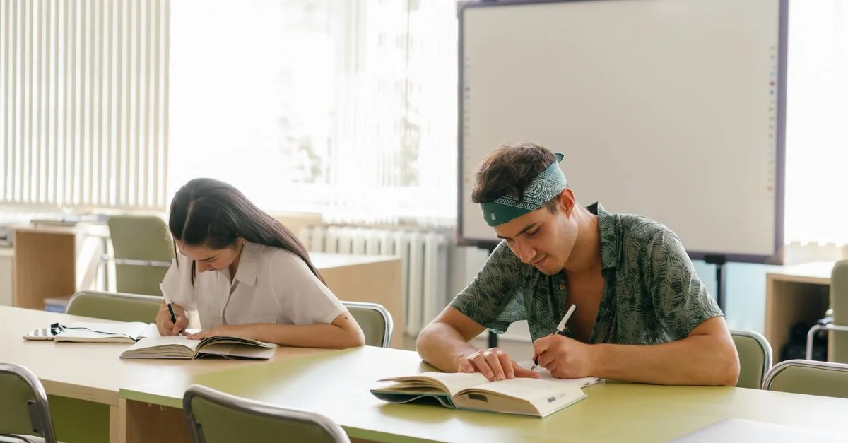 Deux étudiants concentrés sur leurs études dans une salle de classe moderne et lumineuse.
