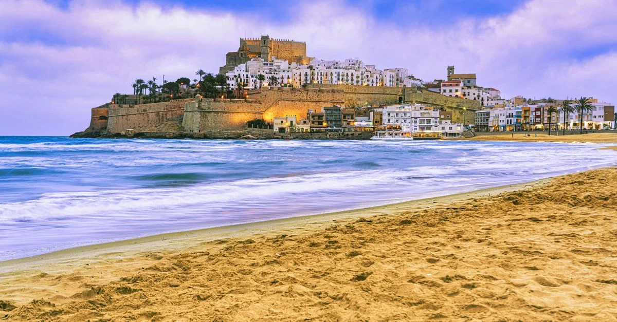 Découvrez la vue côtière saisissante du château de Peñíscola, un site historique en Espagne, sur fond d'un ciel d'été vibrant.