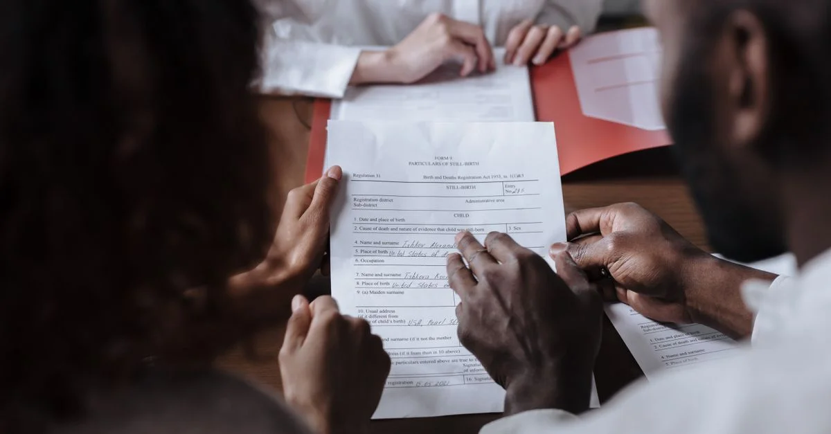 Un couple signe des documents juridiques en collaboration en présence d'un conseiller.