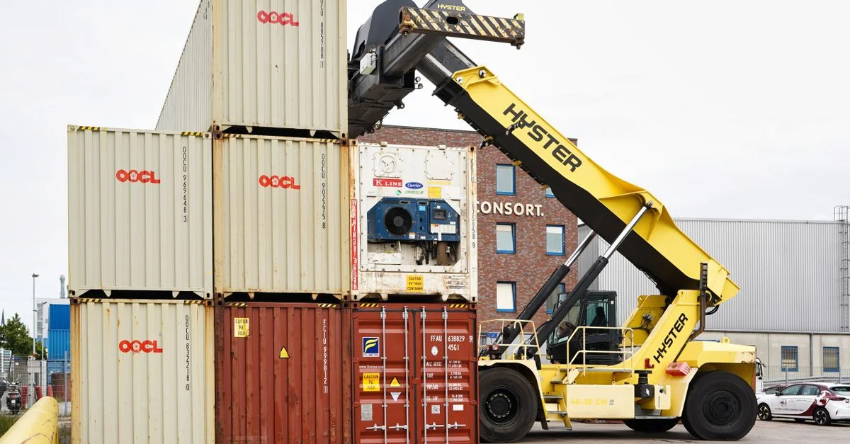 Un gerbeur de conteneurs organisant des conteneurs d'expédition dans le port de Hambourg par temps clair.