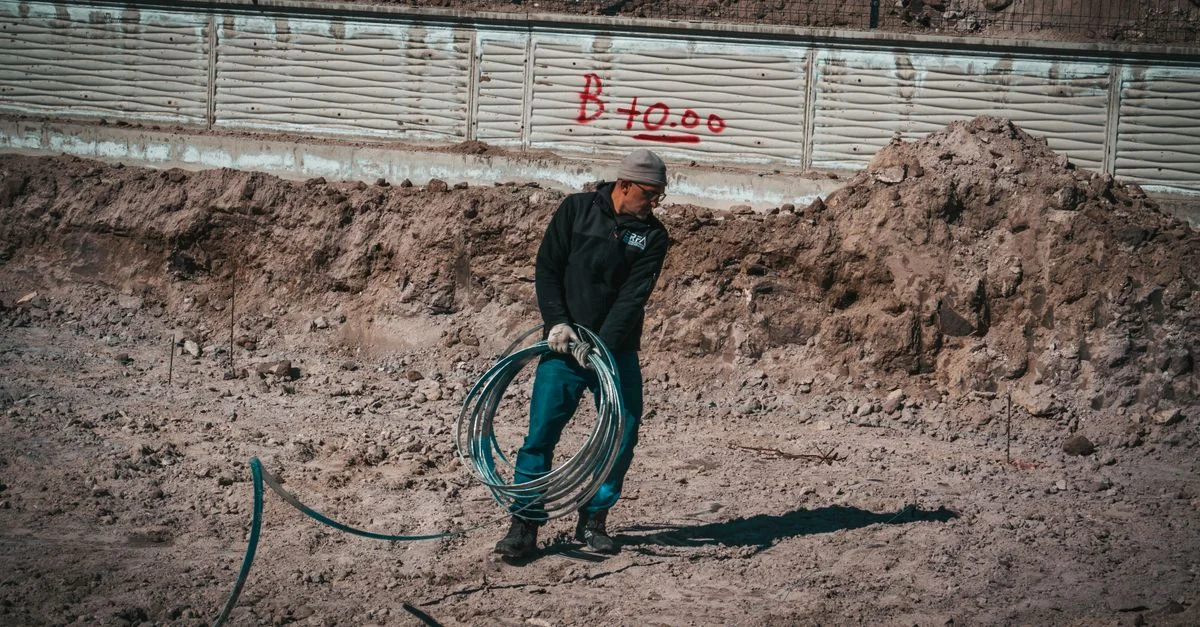 Un ouvrier du bâtiment manipule un câble électrique sur un chantier sablonneux en Turquie.