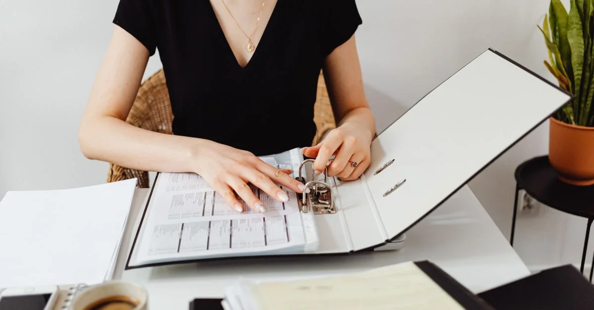 Femme organisant des documents dans un classeur sur un bureau de bureau élégant avec du café.