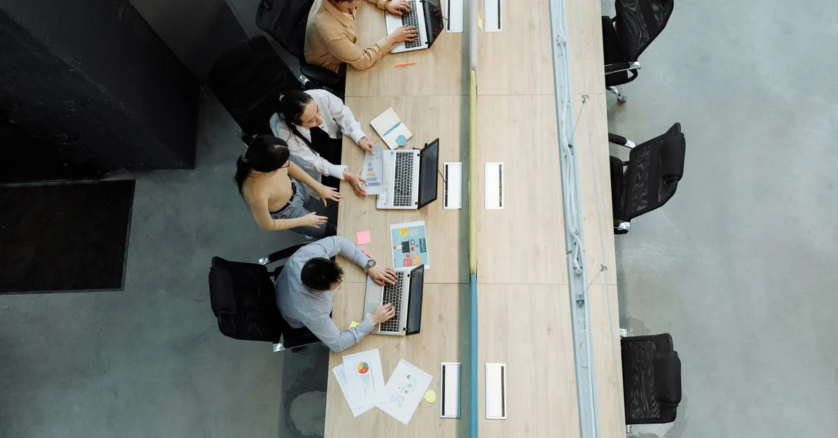 Vue en plongée de collègues travaillant ensemble sur des ordinateurs portables dans un bureau moderne.