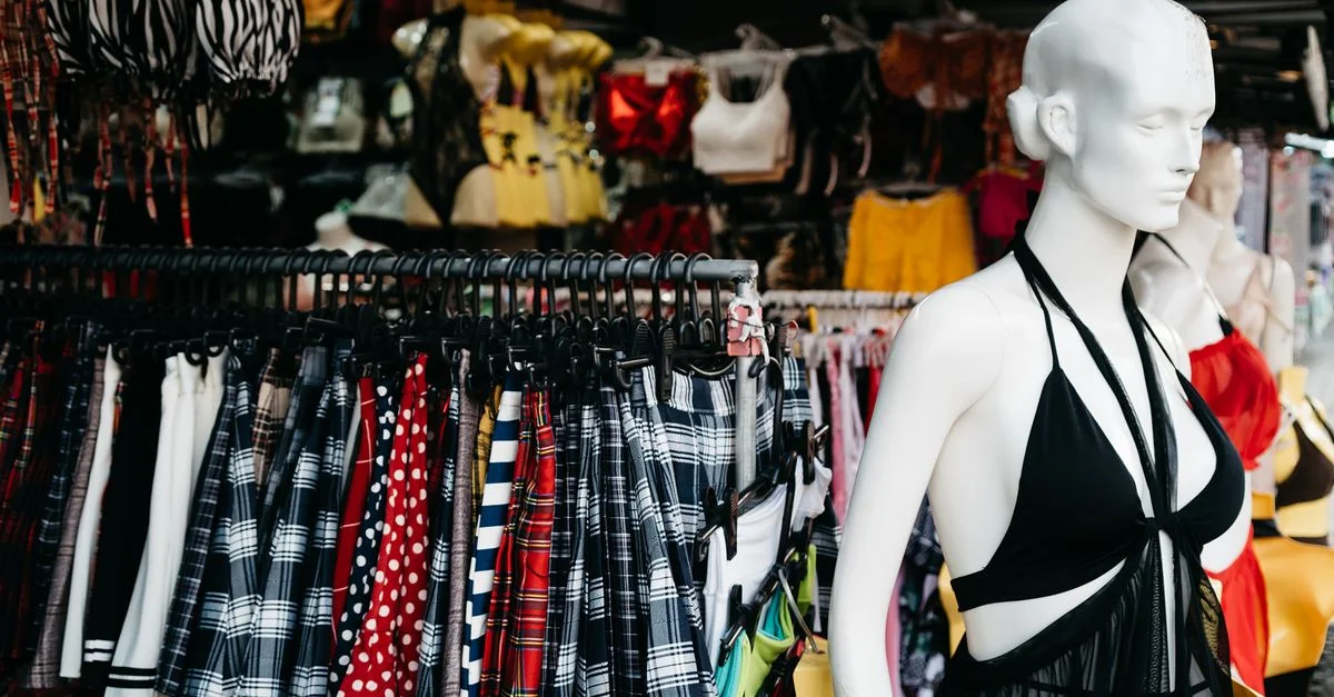 Scène de marché dynamique avec une vitrine de vêtements tendance et un mannequin dans un cadre de vente au détail en plein air.
