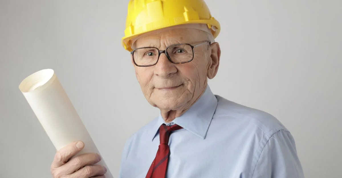 Ingénieur senior en équipement de sécurité tenant des plans, symbolisant l'expérience et le dévouement dans l'ingénierie civile.