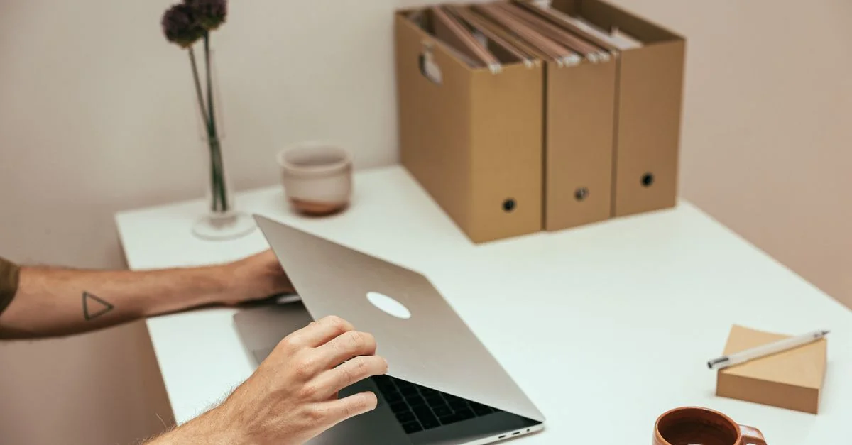 Un espace de travail propre et organisé avec un ordinateur portable, une tasse de café et des fournitures de bureau, parfait pour la productivité.