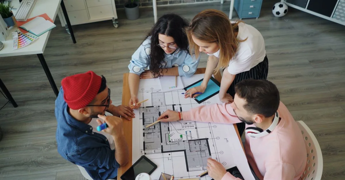 Un groupe diversifié de professionnels créatifs collabore sur un plan d'étage dans un cadre de bureau moderne.