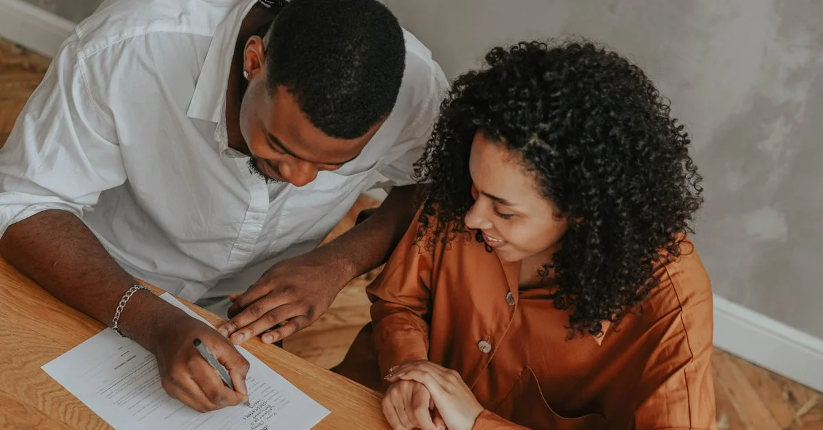 Un couple signant un certificat d'adoption à une table, vu d'en haut.