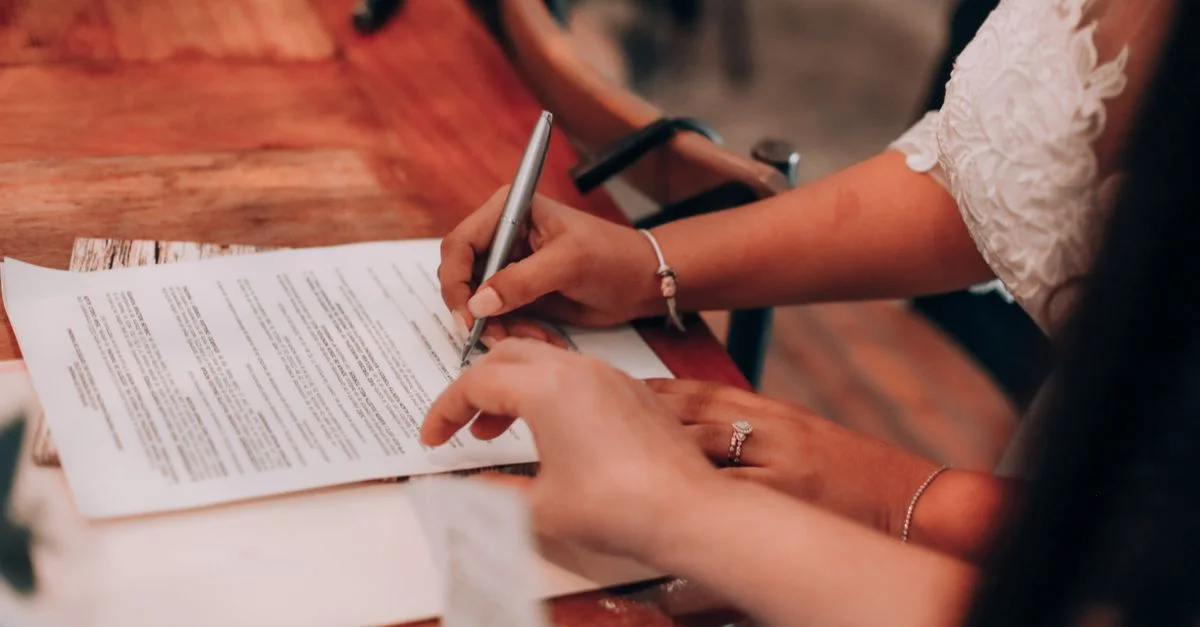 Des mains signant un document important sur une table en bois, symbolisant l'accord et l'engagement.