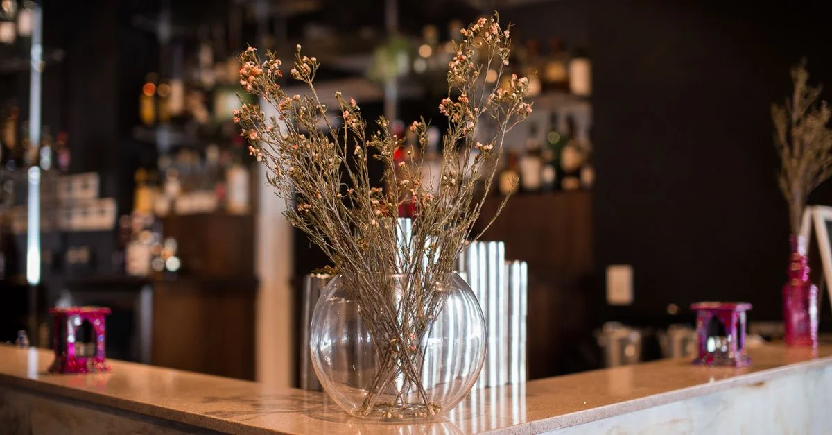 Fleurs séchées élégantes dans un vase rond sur un bar moderne avec un comptoir en marbre.