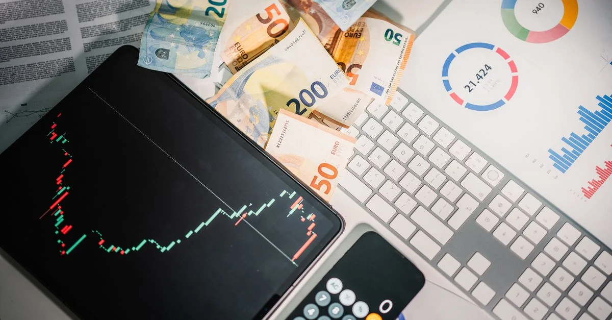 Vue de dessus des outils financiers avec des billets en euros sur un bureau montrant les tendances du marché et des graphiques.