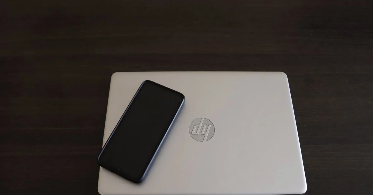 Gros plan d'un smartphone reposant sur un ordinateur portable HP, symbolisant l'intégration de la technologie moderne.