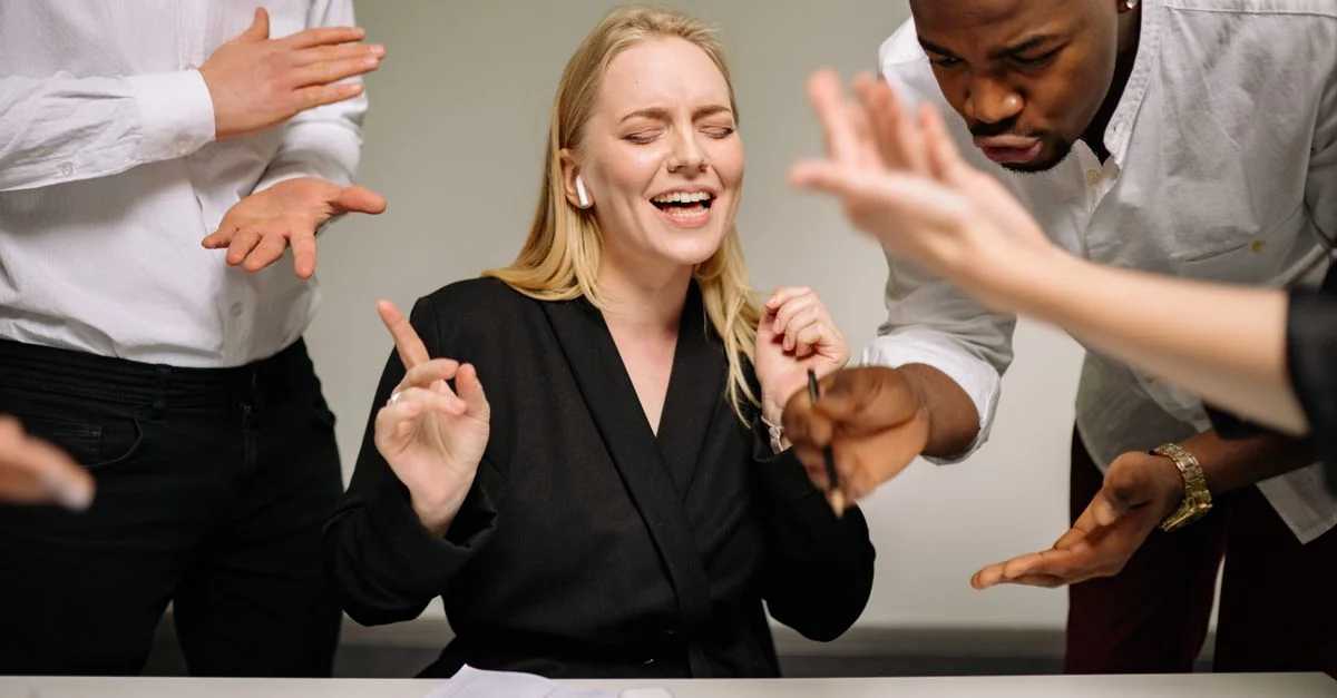 Équipe de travail diversifiée participant à une discussion animée au bureau avec des gestes expressifs et une collaboration ciblée.