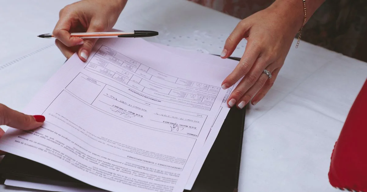 Une vue détaillée des mains travaillant avec des documents et un stylo sur un bureau, idéal pour des thèmes d'affaires.