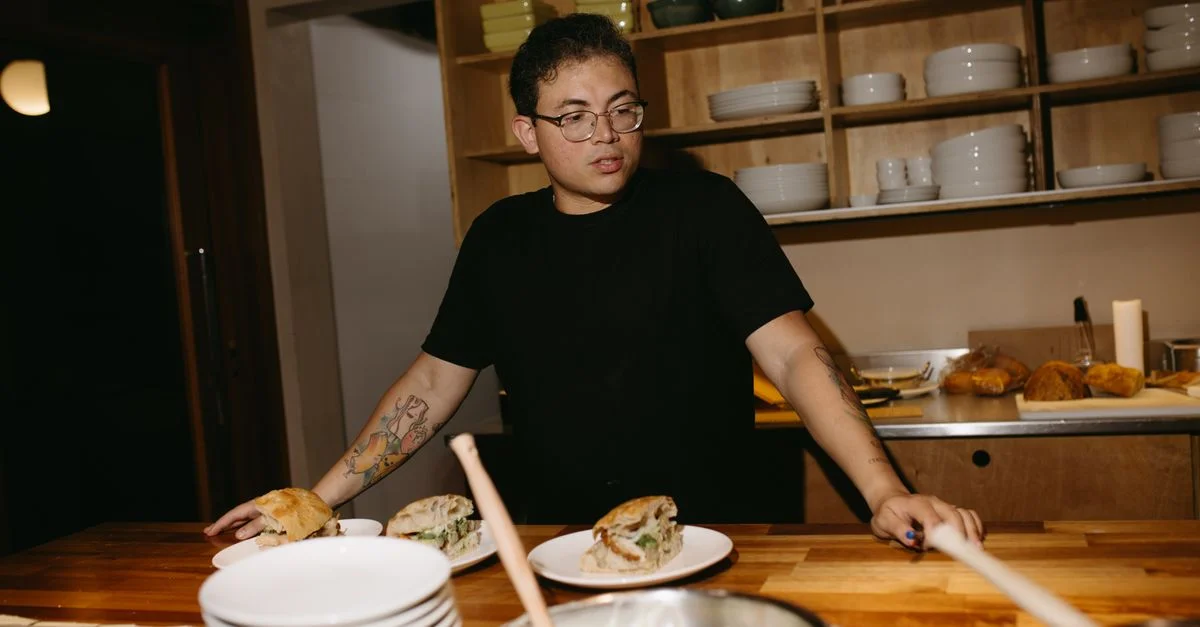 Cuisinier travaillant dans une cuisine moderne préparant des sandwiches avec des ingrédients frais.
