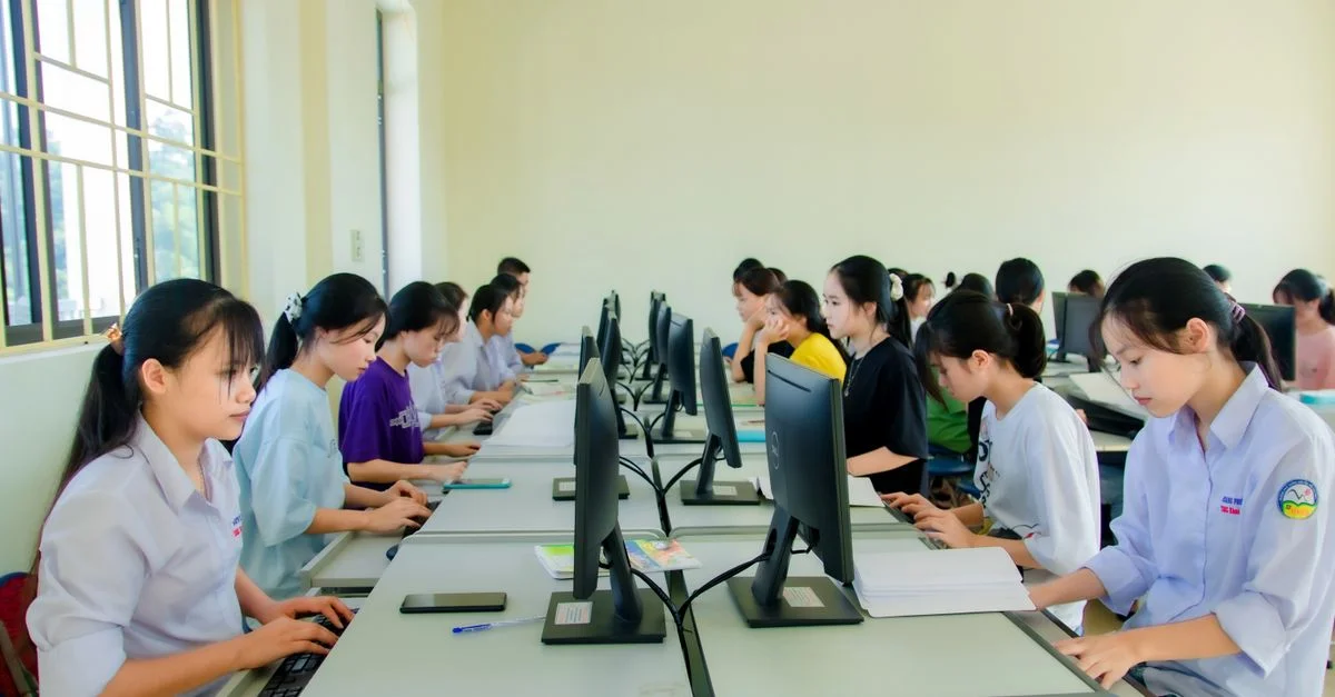 Un groupe d'étudiants se concentrant sur des ordinateurs lors d'un cours dans un cadre universitaire, travaillant à l'intérieur.