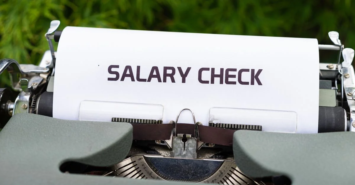 Gros plan d'une machine à écrire vintage tapant 'Chèque de Salaire' sur du papier, symbolisant la paie et les finances.